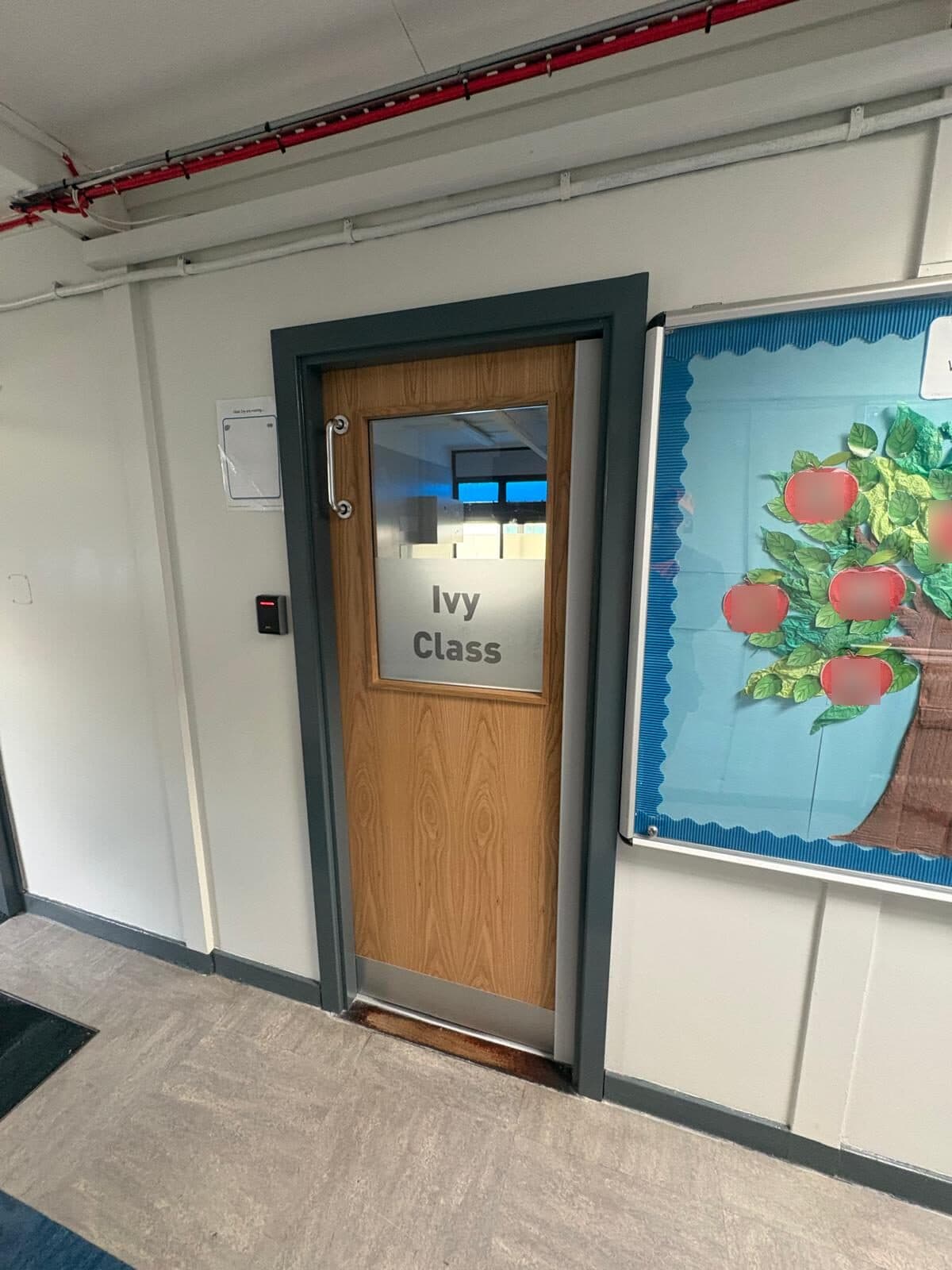 Oak-effect classroom fire door with a frosted vision panel and full-width kick plate in a Knowsley school