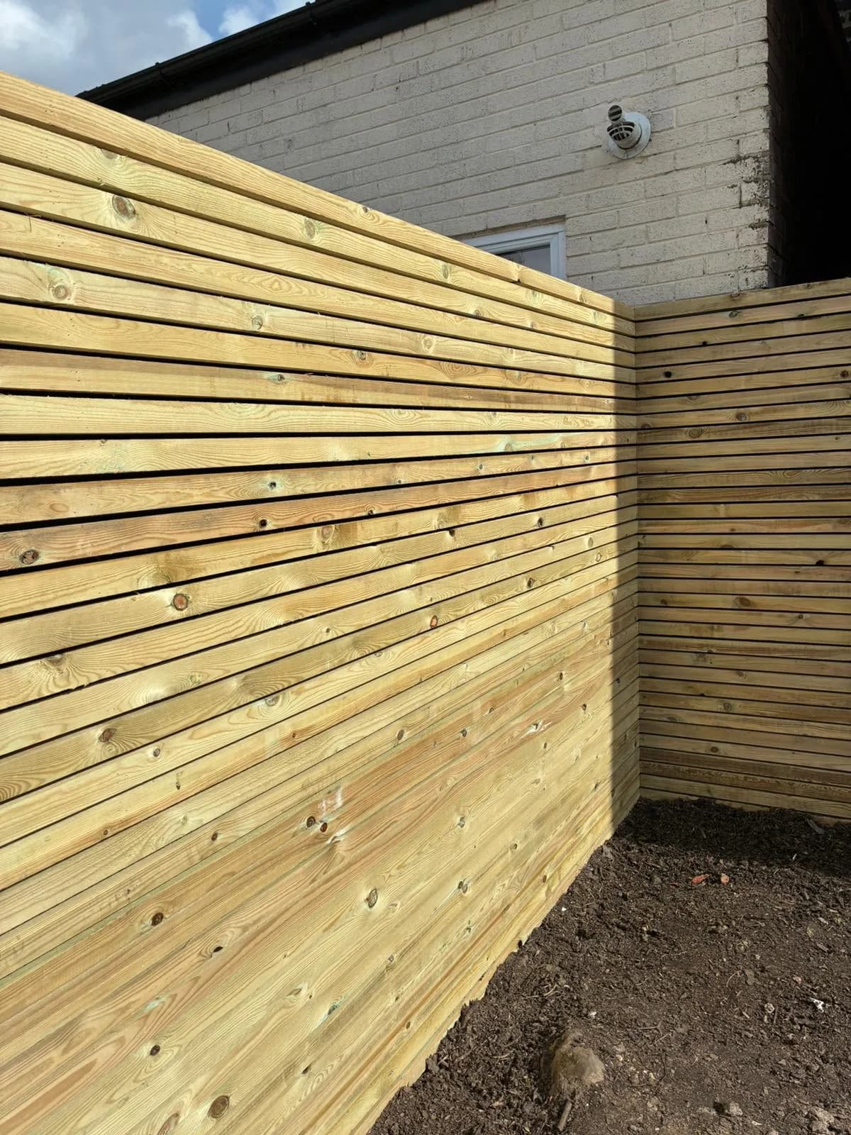 Close view of the new slatted fence where one run of slats meets the next at the corner