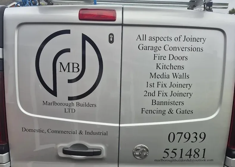 The back doors of the Marlborough Builders van, with the MB roundel, the list of joinery trades and the phone number painted on